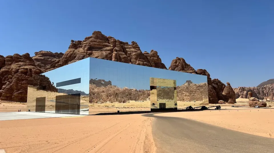 Ein Gebäude mit einer reflektierenden Spiegelfassade in der Wüste von Saudi Arabien.