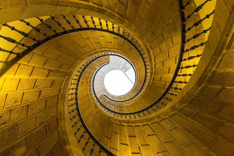 Blick von unten auf die steinerne Wendeltreppe zum Oberlicht.